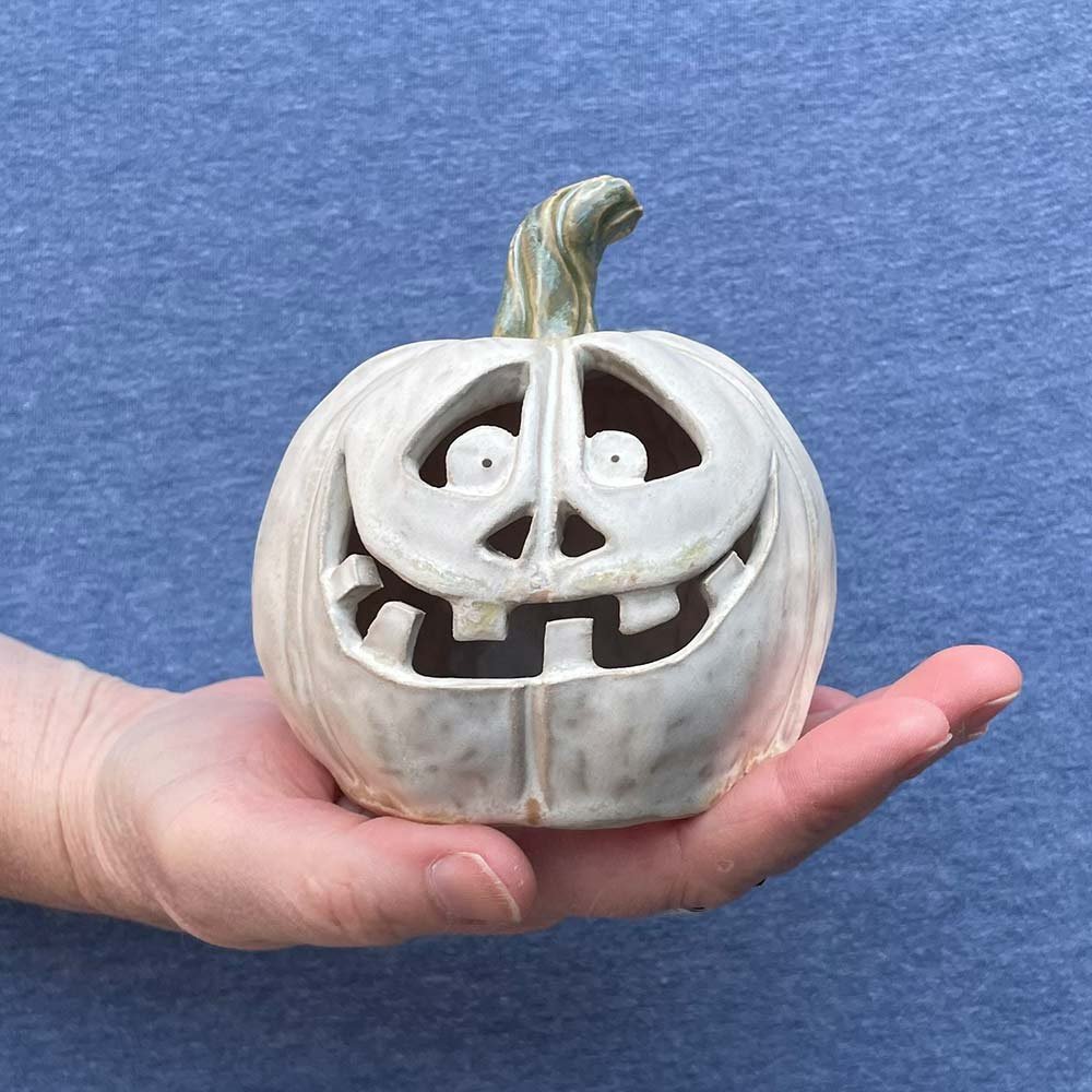 Carved white ceramic pumpkin by Lucy Ormsby Pottery in the hand